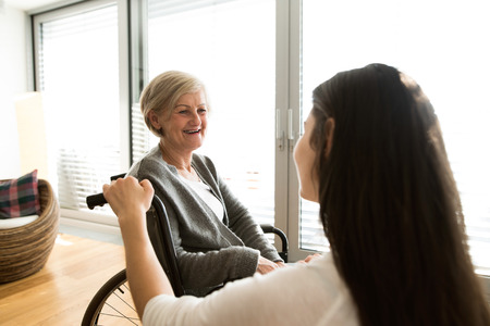 Disabled senior woman in wheelchair with her young daugher.の写真素材