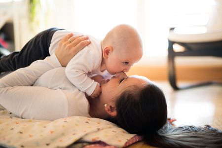 Mother lying on the floor holding her cute baby sonの写真素材