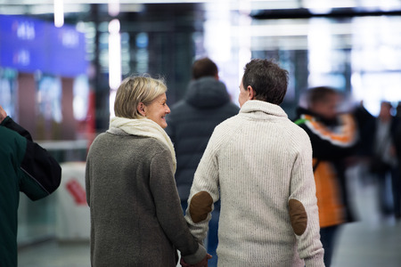 Senior couple in hallway of subway, holding hands. Rear view.の写真素材