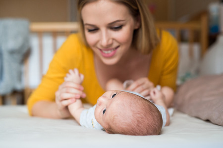 Mother with her newborn baby son lying on bed