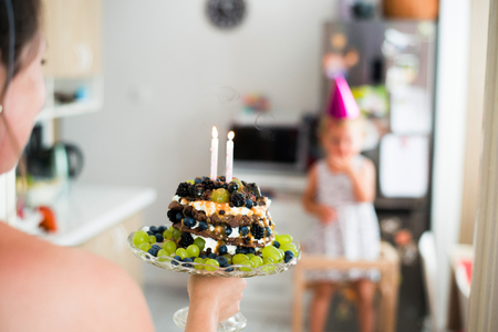 Unrecognizable mother giving daughter birthday cake with candlesの写真素材