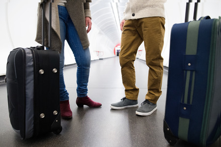 Unrecognizable couple in hallway of subway with trolley luggage.