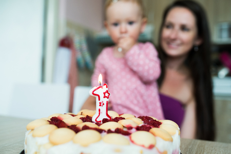 Mother with her cute daughter and birthday cake with candleの写真素材