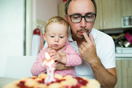 Father with his cute daughter eating her birthday cakeの写真素材