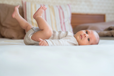 Cute newborn baby boy at home lying on bed