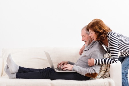 Beautiful senior couple working on laptop. Studio shot.の写真素材