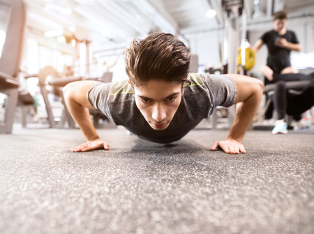 Young fit hispanic man in gym doing push ups