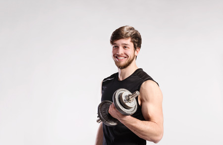 Handsome fitness man holding dumbbell, studio shot.の写真素材