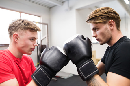 Two fit handsome men in gym boxing.の写真素材
