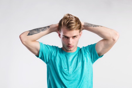 Young handsome hipster man in turquoise t-shirt, studio shot.の写真素材