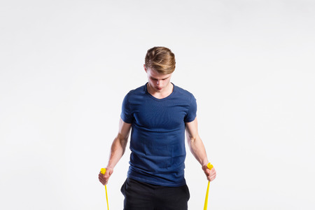 Fitness man working out with resistance bands, studio shot.の写真素材