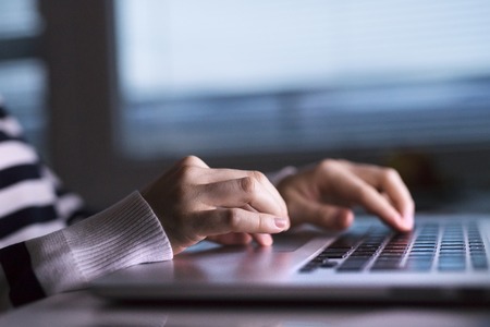 Hands of unrecognizable woman sitting at desk working on laptop.の写真素材