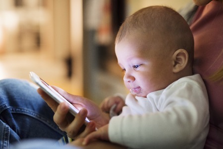 Unrecognizable mother with son in the arms, holding smartphone