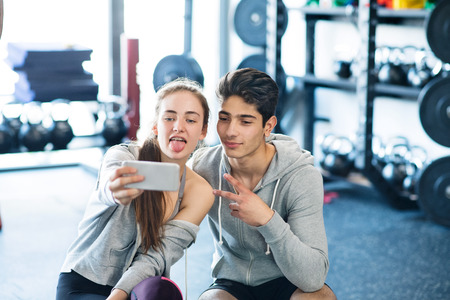 Fit couple in modern crossfit gym with smartphone.の写真素材