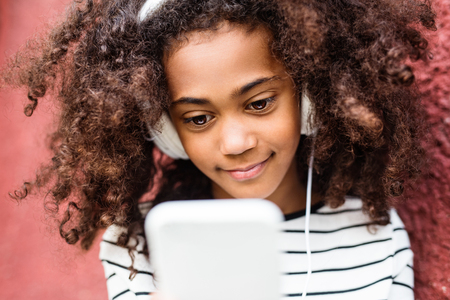 Beautiful african american girl with smart phone and earphones.の写真素材