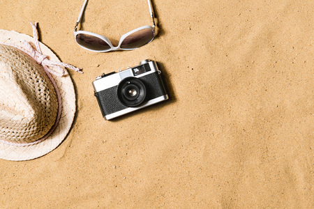 Sunglasses, wicker hat and camera. Sand background.の写真素材