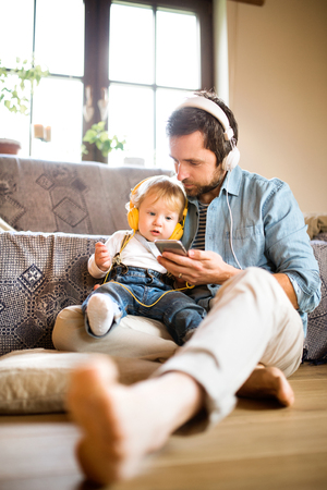 Father and son with smartphone and earphones, listening music.の写真素材