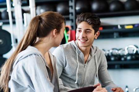 Beautiful young fit couple in modern crossfit gym talking.の写真素材
