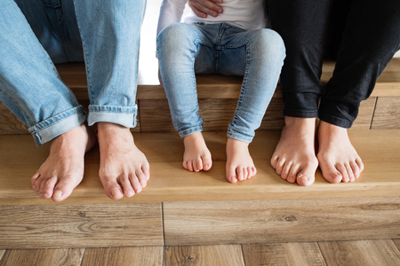 Beautiful young family. Bare feet of mother, father and daughterの写真素材