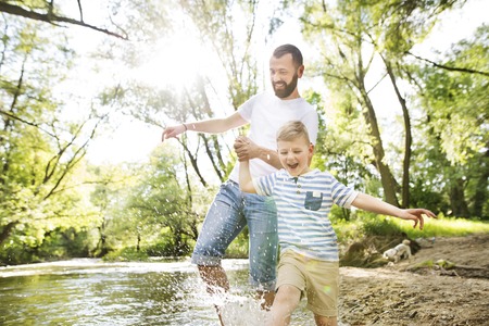 Young father with little boy in the river, sunny spring day.の写真素材