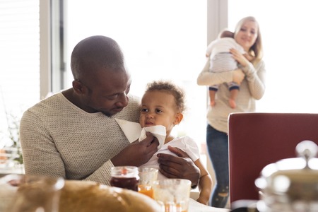 Young interracial family with little children having breakfast.の写真素材