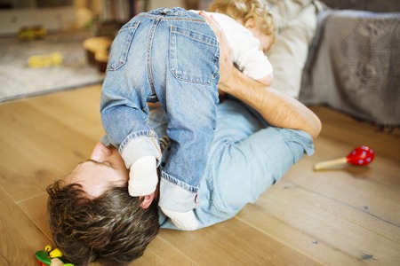 Young father at home playing with his little son.の写真素材