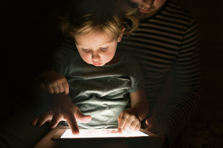 Father with tablet and little daughter at home at night.の写真素材
