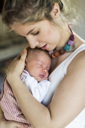 Young mother at home holding her newborn baby daughterの写真素材