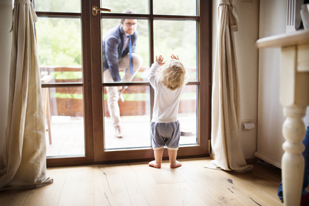 Businessman coming home, little son at the door welcoming him.の写真素材