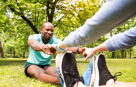 Running couple stretching and warming up in park before trainingの写真素材