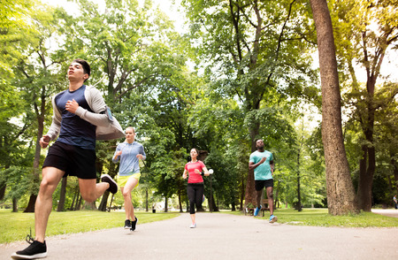 Group of young athletes running in green sunny park.の写真素材