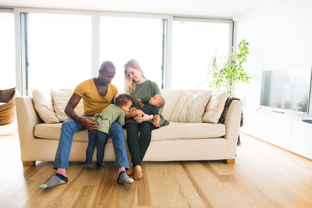 Young interracial family with little children at home.