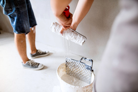 Unrecognizable young couple painting walls in their new house.の写真素材