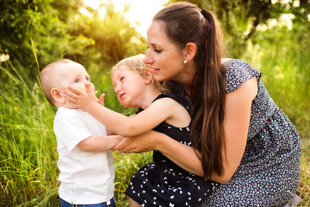 Young mother with little children in sunny summer natureの写真素材
