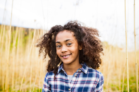 African american girl in checked shirt outdoors in field.の写真素材