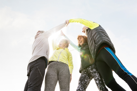 Group of senior runners outdoors, resting, holding hands.の写真素材