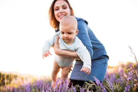 Young mother in nature with baby son in the arms.