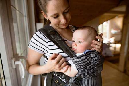 Beautiful mother with her cute little son in baby carrierの写真素材
