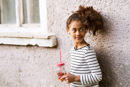 Beautiful african american girl with glass and straw, drinking.の写真素材
