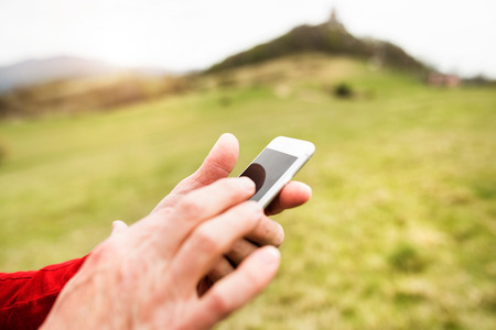 Unrecognizable senior sportsman in nature with smart phone.
