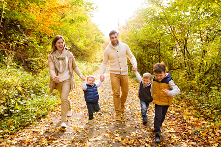 Beautiful young family on a walk in autumn forest.の写真素材