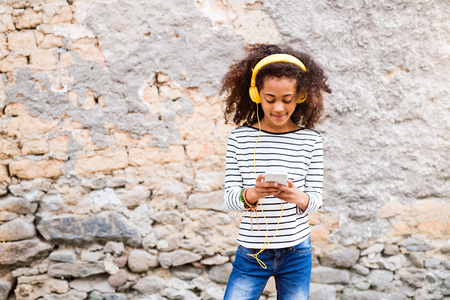 Beautiful african american girl with smart phone and earphones.の写真素材