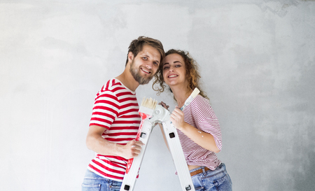 Young couple painting walls in their new house.の写真素材