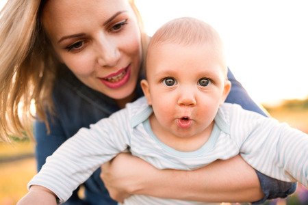 Young mother in nature with baby son in the arms.の写真素材