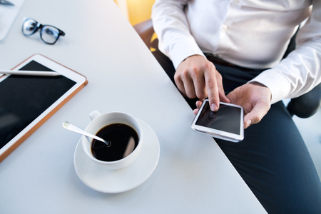 Businessman with smartphone and tablet in his office.の写真素材