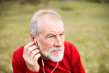 Active senior runner in nature with smart phone and earphones.の写真素材