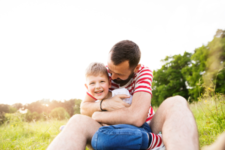 Hipster father and little son on green meadow. Sunny summer day.の写真素材