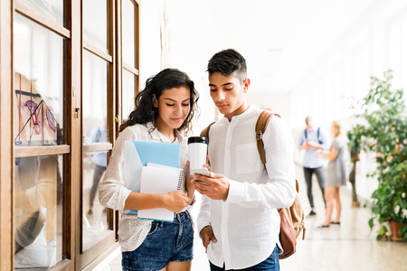 Attractive teenage student couple in high school hall.の写真素材