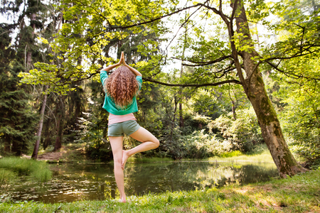Beautiful girl practices yoga in the morning forest.の写真素材
