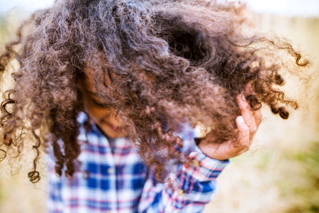 African american girl in checked shirt outdoors in field.の写真素材